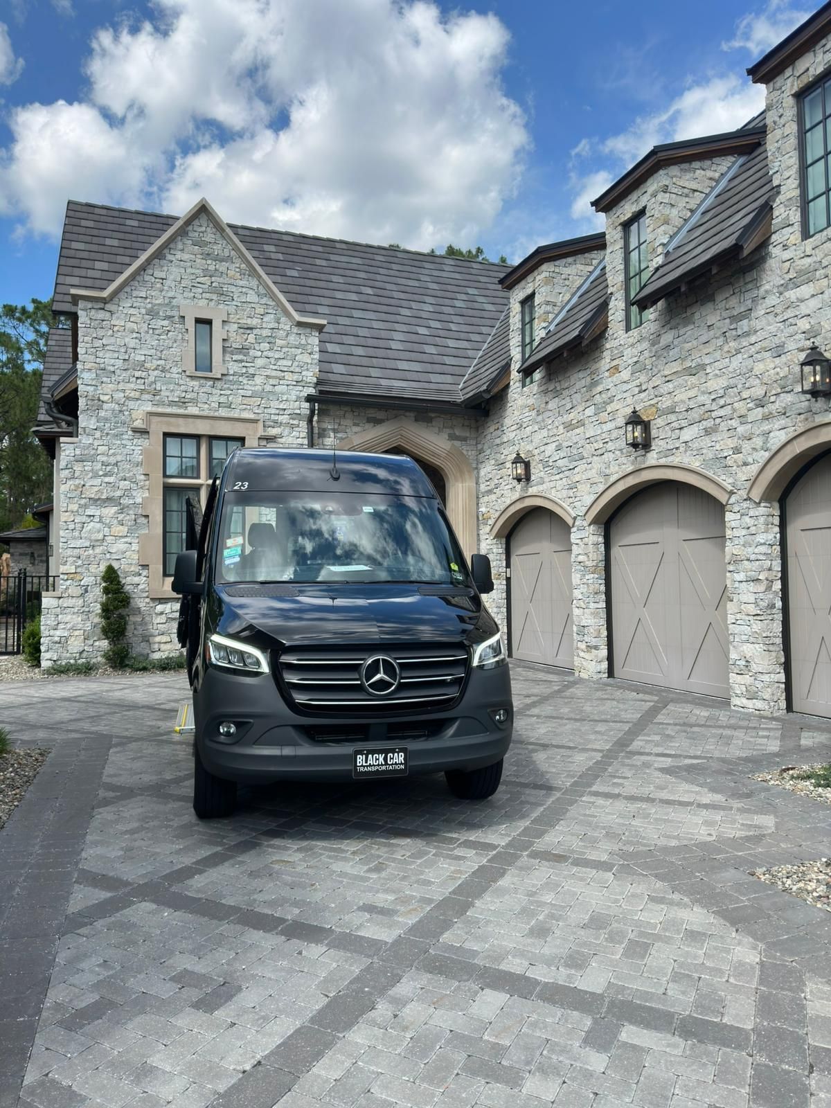 A black van is parked in front of a large stone building.