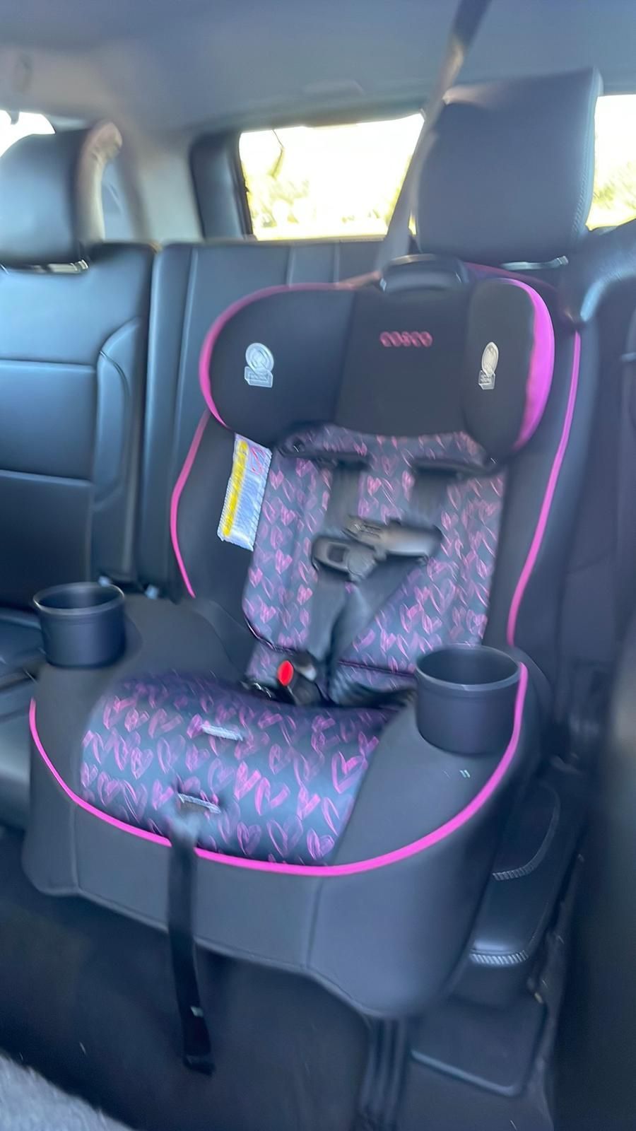 A car seat is sitting in the back seat of a car.