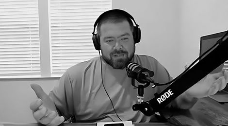 A man wearing headphones and a microphone is giving a thumbs up.