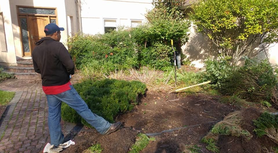 A man is standing in the dirt in front of a house.