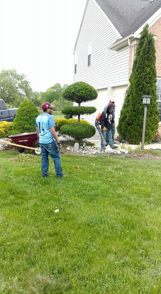 A group of men are standing in a lush green lawn in front of a house.