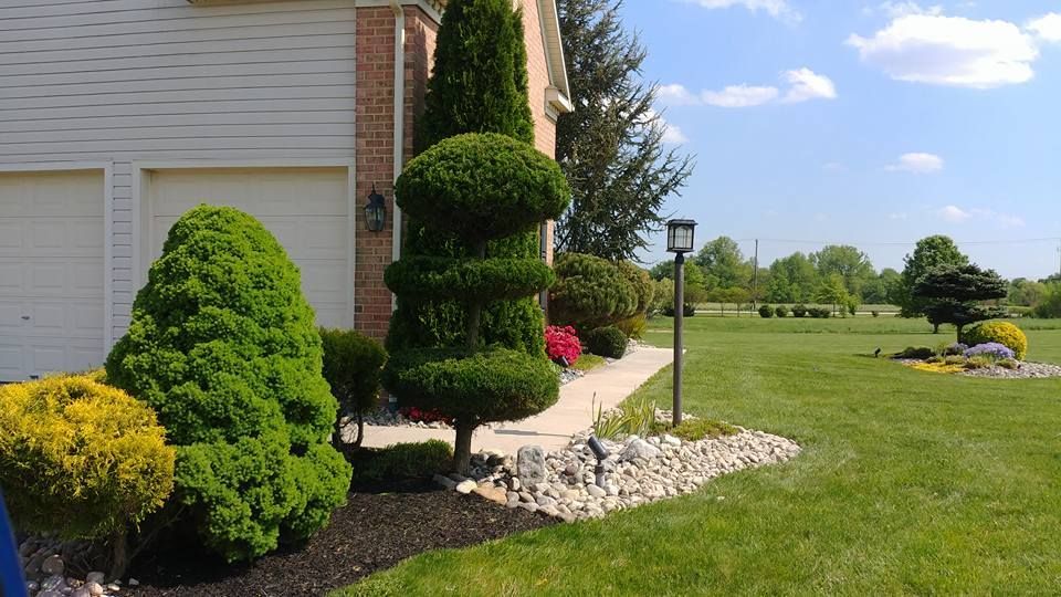 A house with a lush green lawn and trees in front of it.
