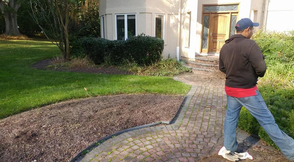 A man is standing on a sidewalk in front of a house.