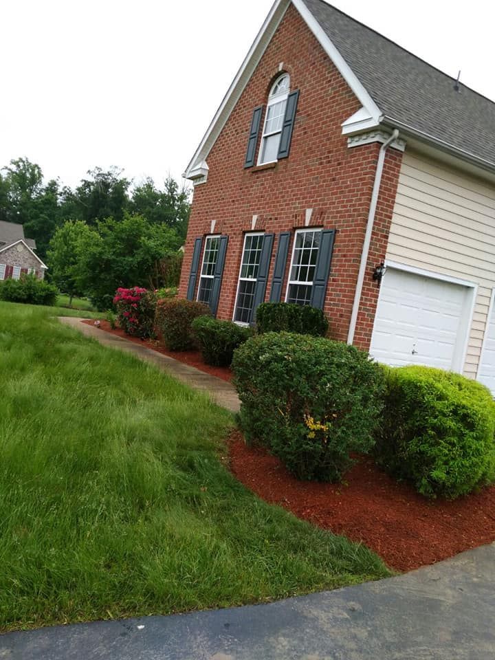 A brick house with a garage and a lush green lawn in front of it.