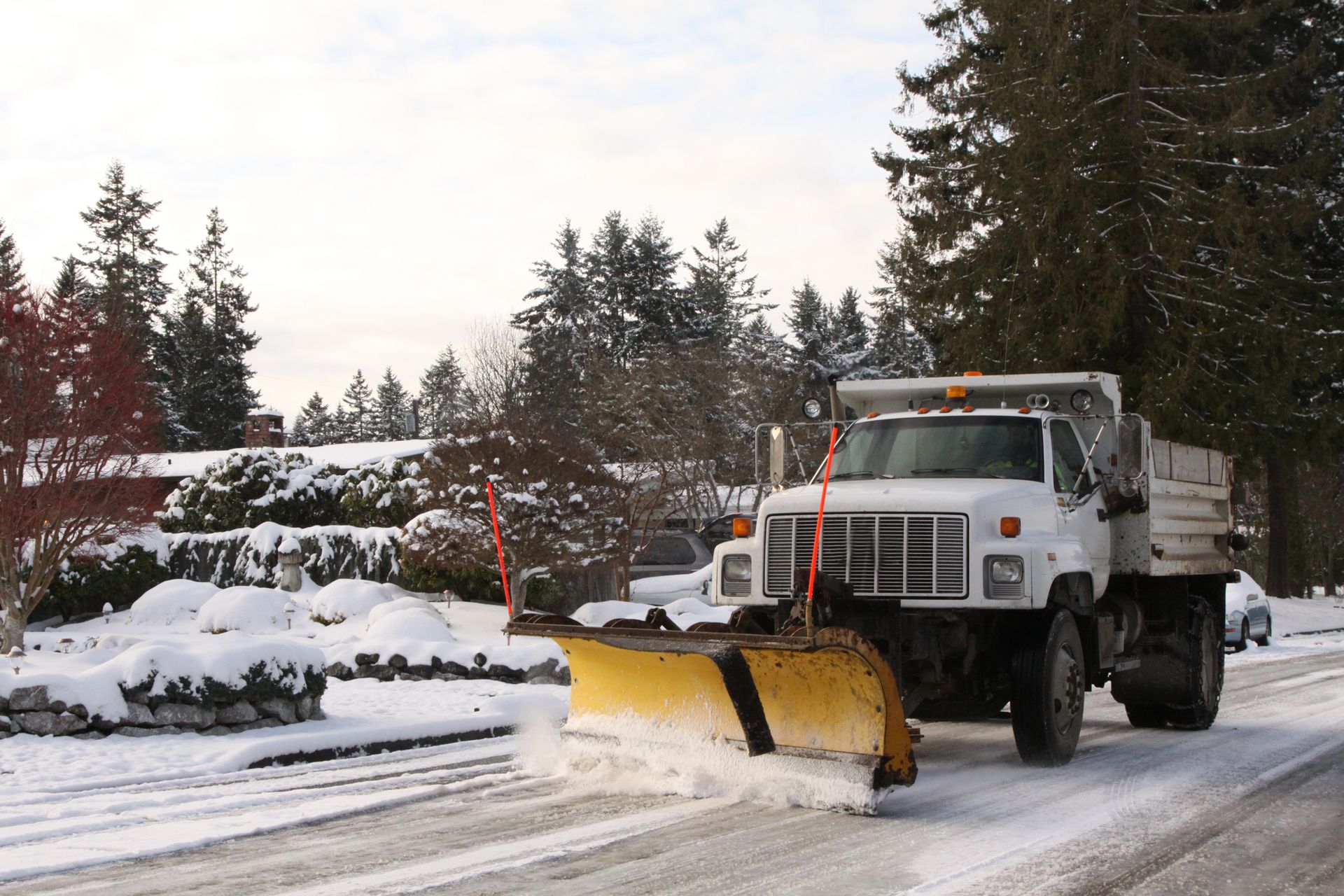 A snow plow is driving down a snowy road