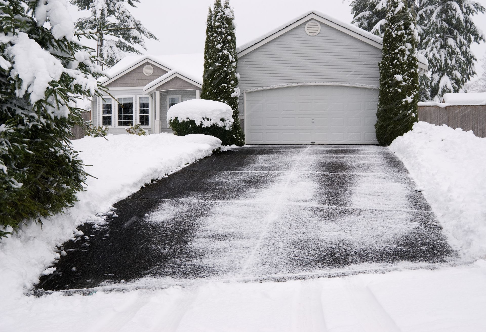 A snowy driveway with a house in the background
