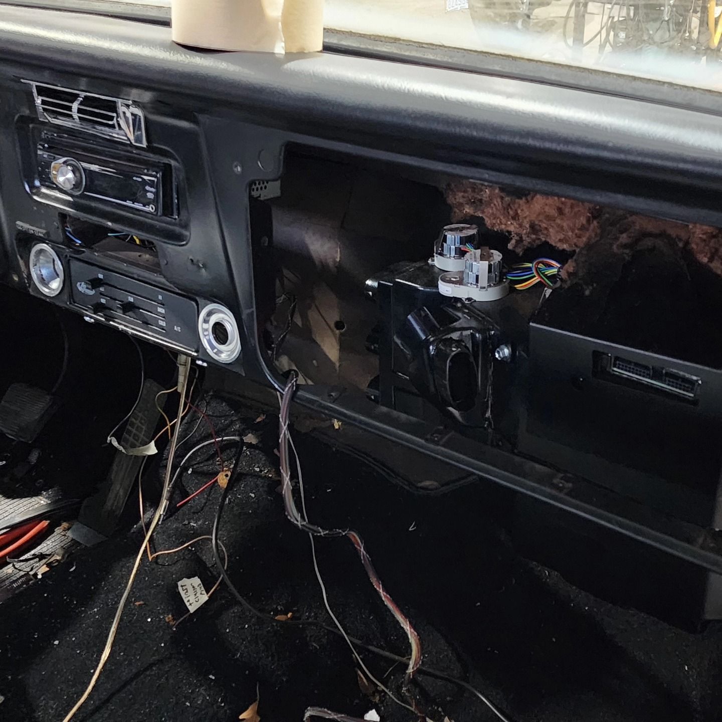 Car interior with dashboard removed, exposing wiring and an open glove compartment area.