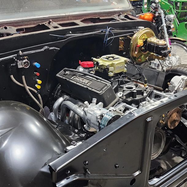 Custom car engine bay with exposed black components and a gold turbocharger.