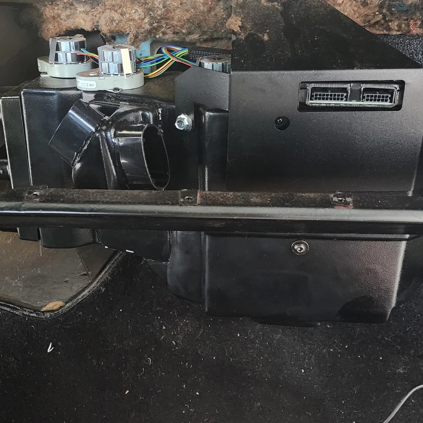 Black electronic device with wiring and connectors mounted under a dusty surface