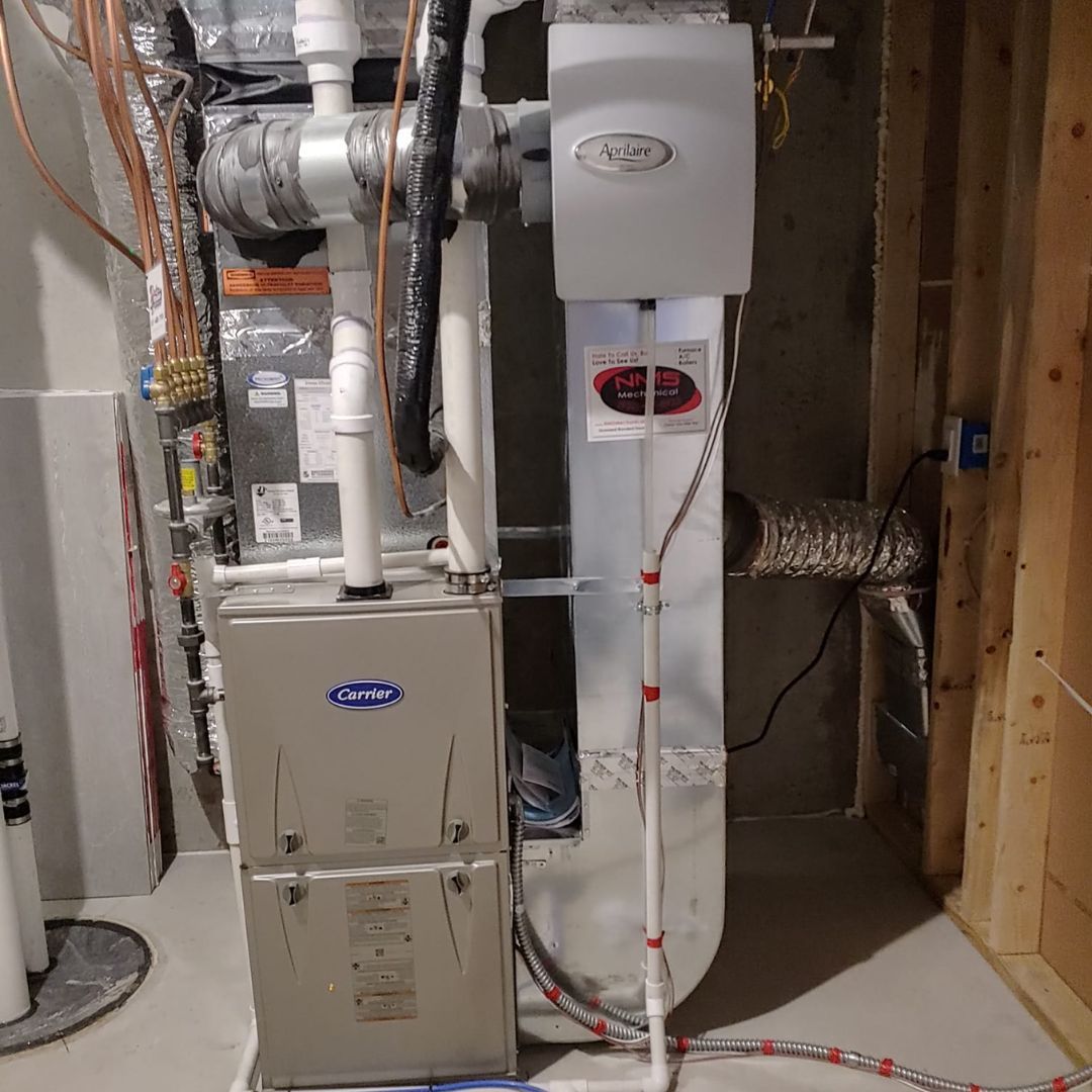 A water heater is sitting next to a furnace in a basement.