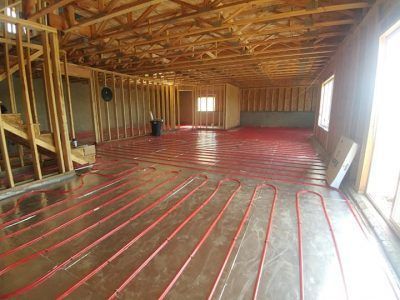 A large room in a house under construction with red pipes on the floor.