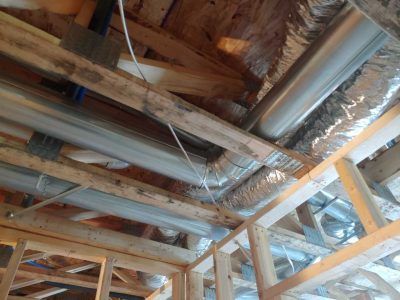 The ceiling of a house under construction with pipes coming out of it.