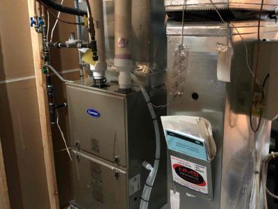 A furnace is sitting in a room next to a heater.