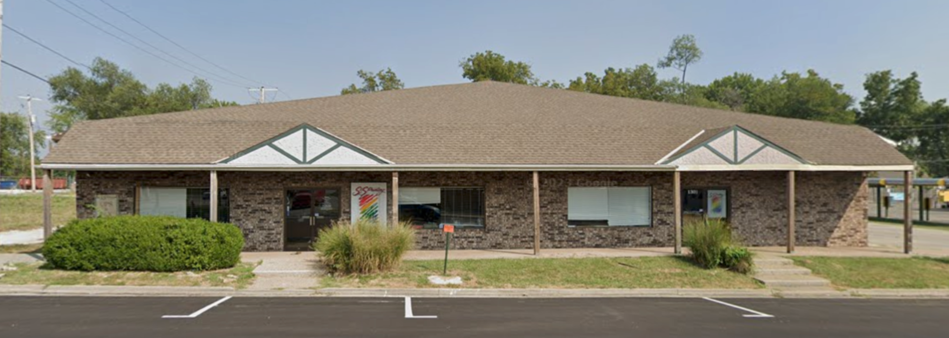 A small brick building with a parking lot in front of it.