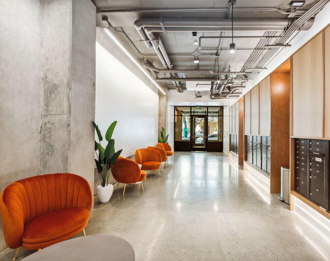 A long hallway with orange chairs and a table