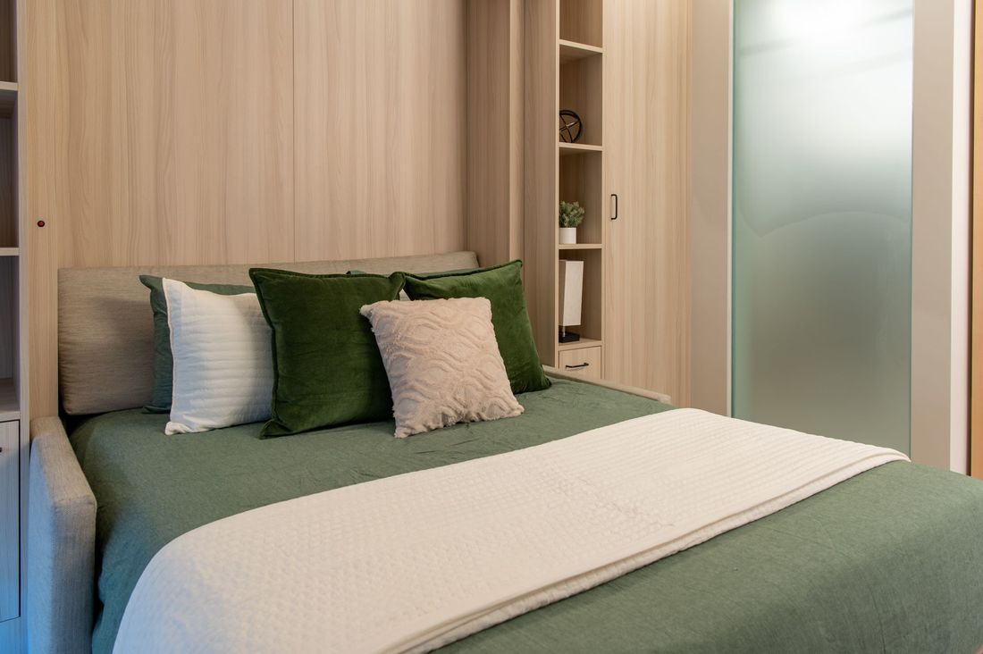 A bed with green sheets and pillows in a bedroom.