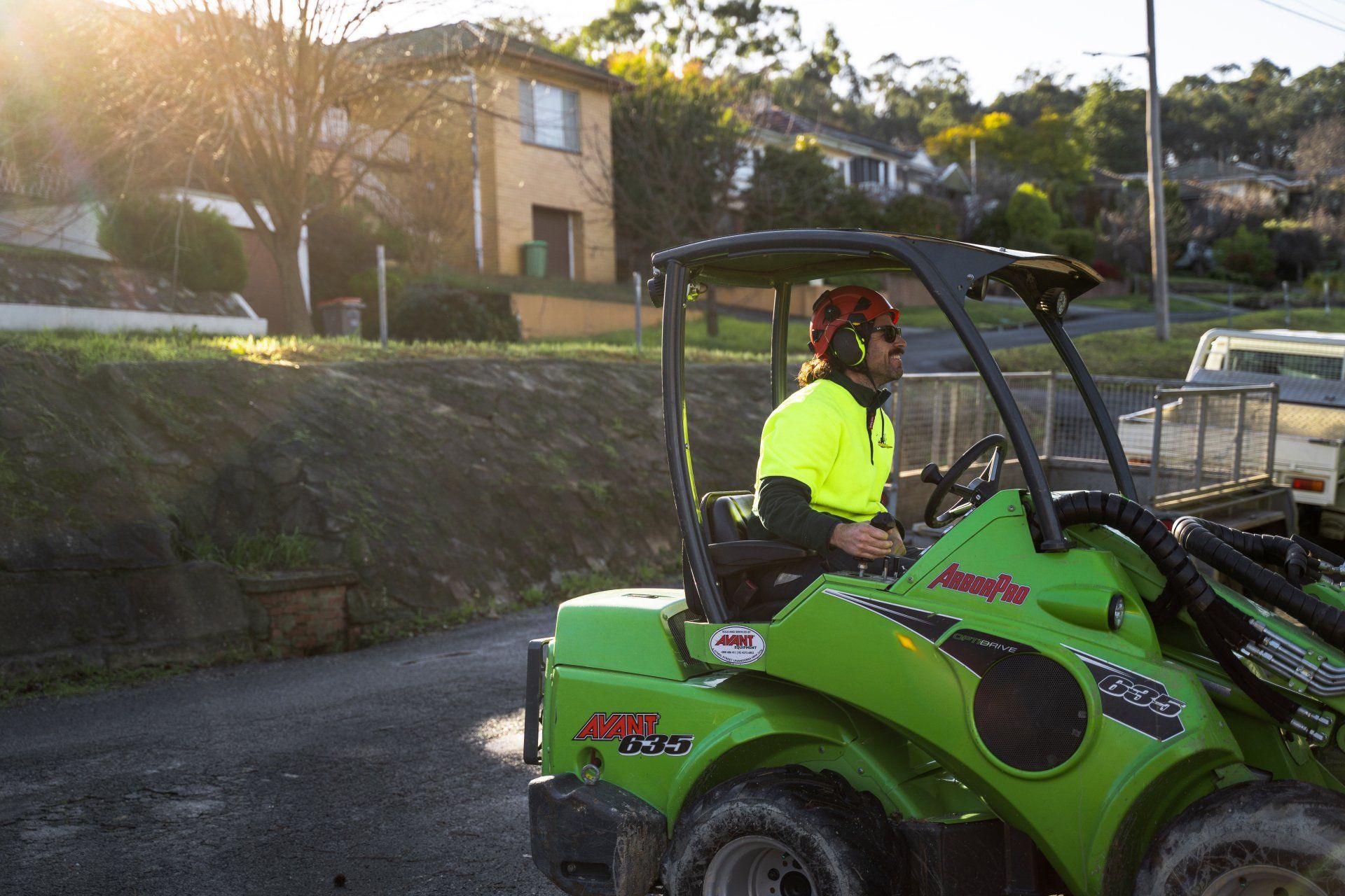 A man is driving a green tractor down a dirt road.