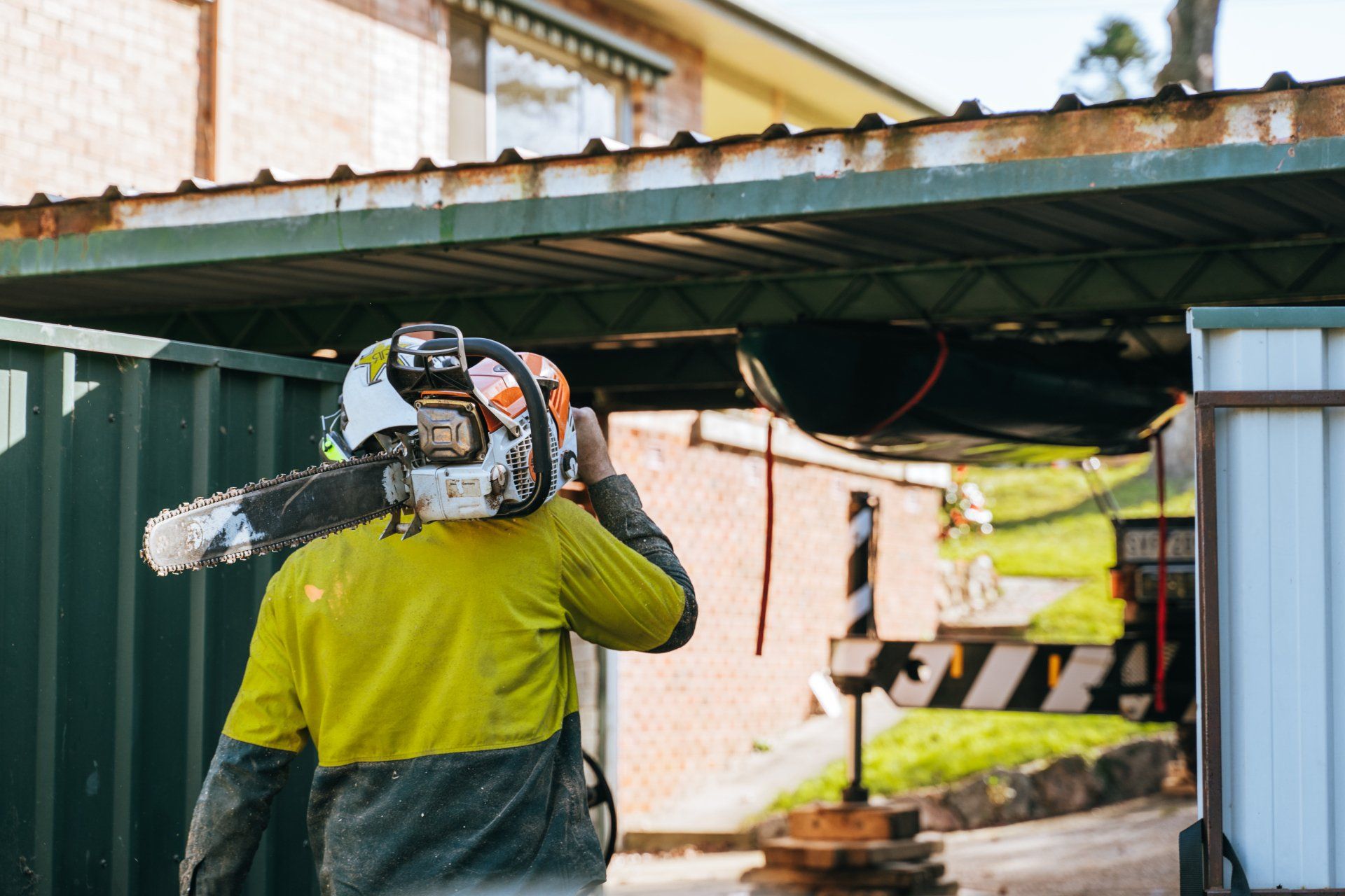 A man wearing a helmet and carrying a chainsaw on his shoulder.