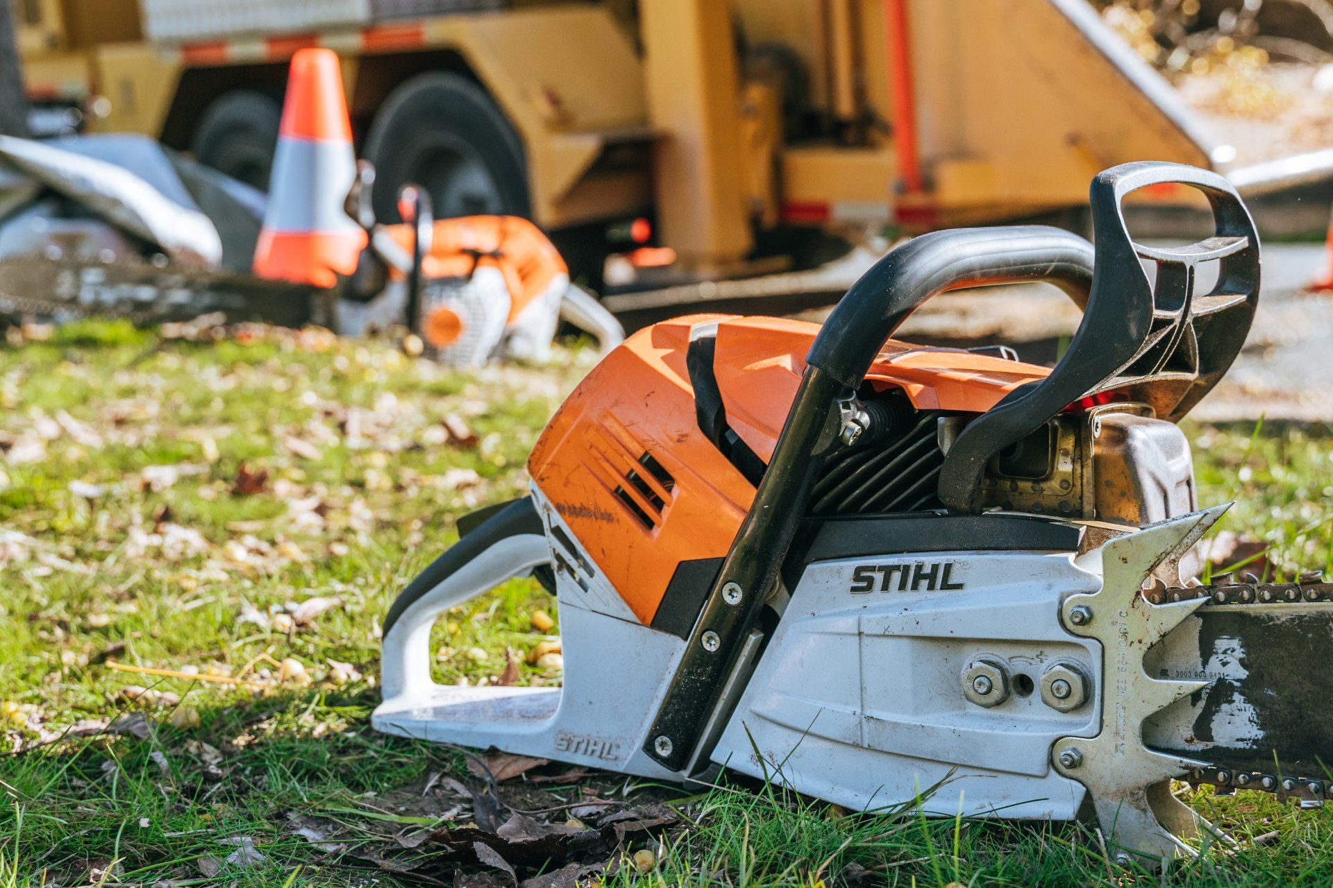 A stihl chainsaw is sitting on top of a lush green field.