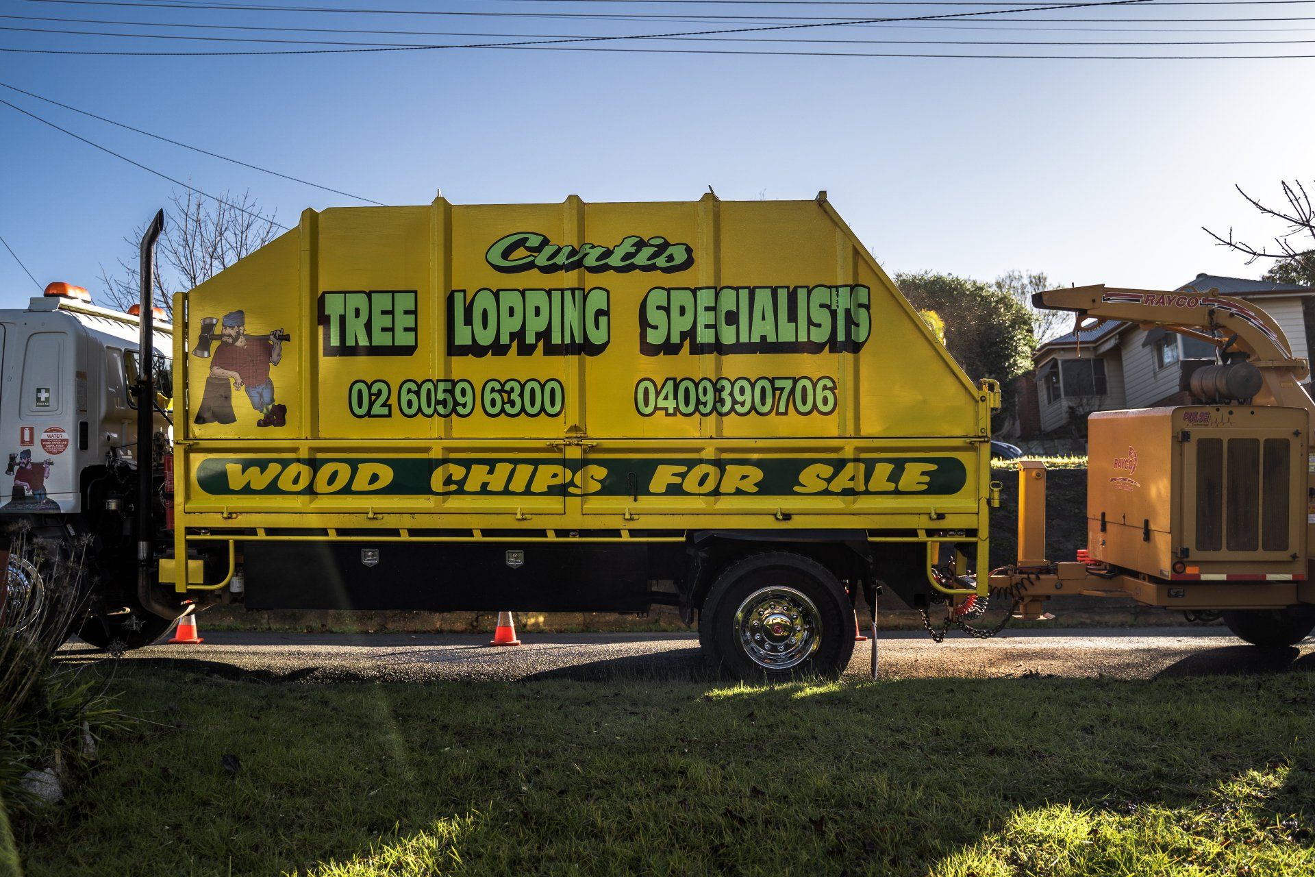 A yellow truck that says tree lopping specialist wood chips for sale