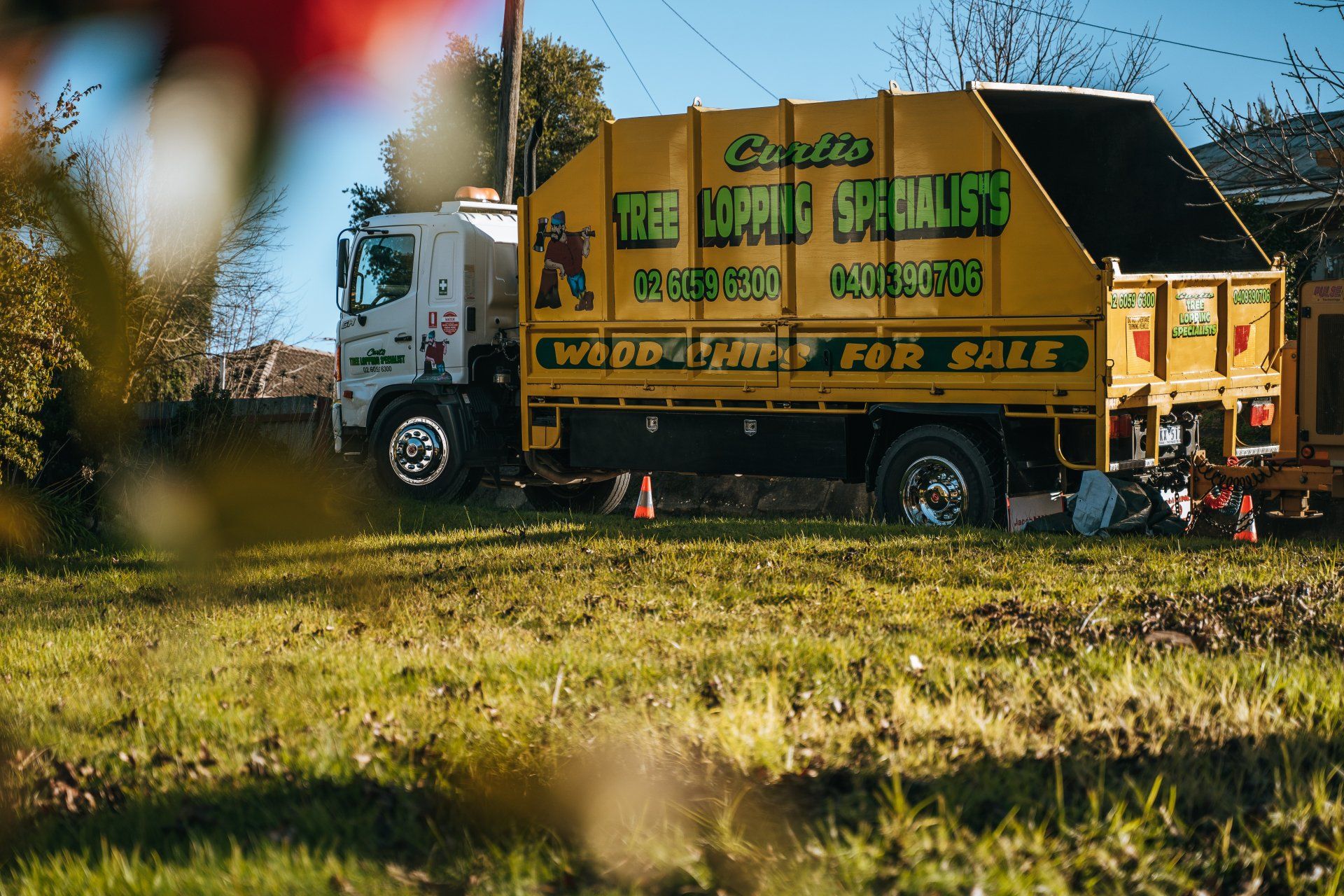 A yellow truck is parked in a grassy field.