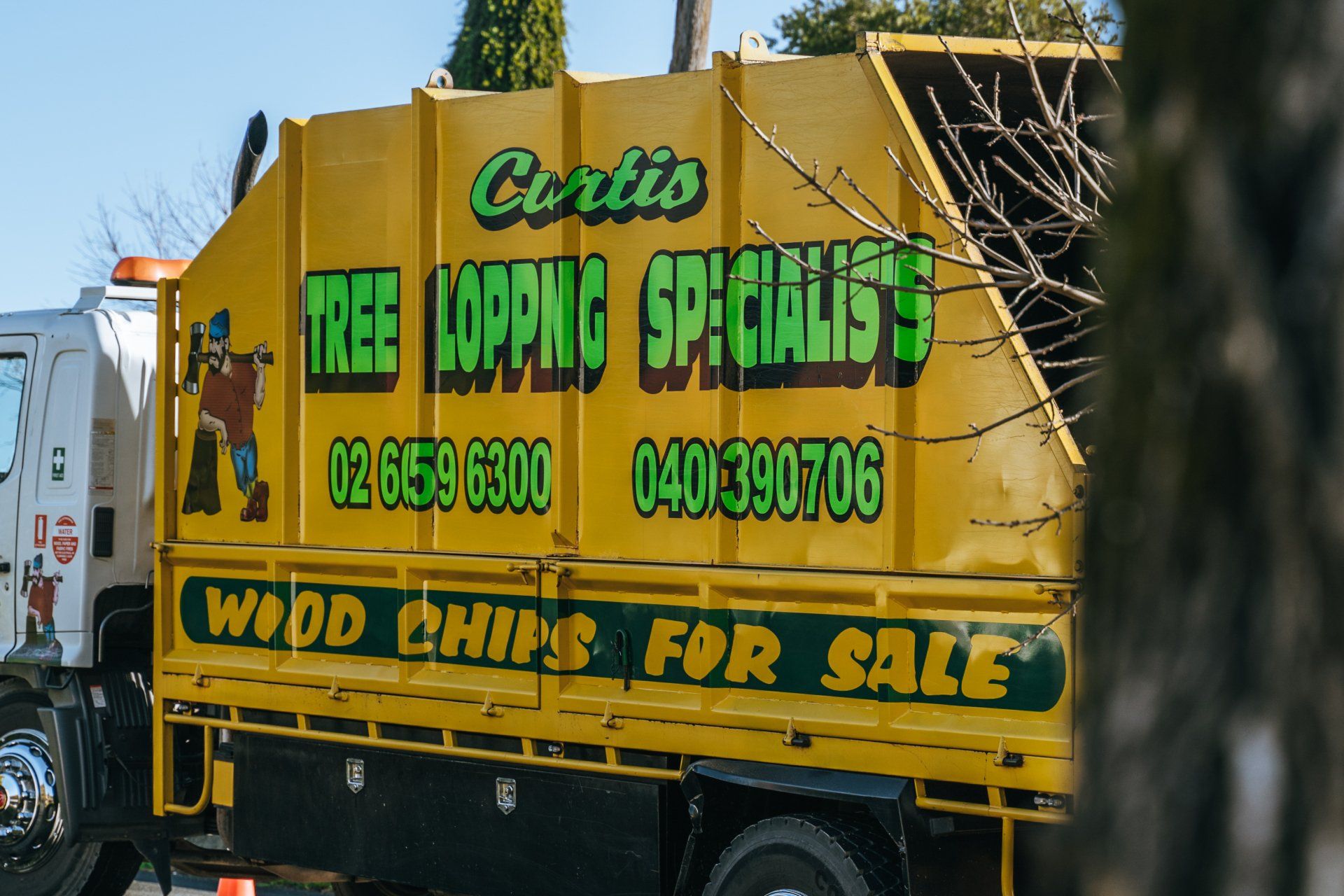 A yellow truck that says corlis tree topping specialists on it