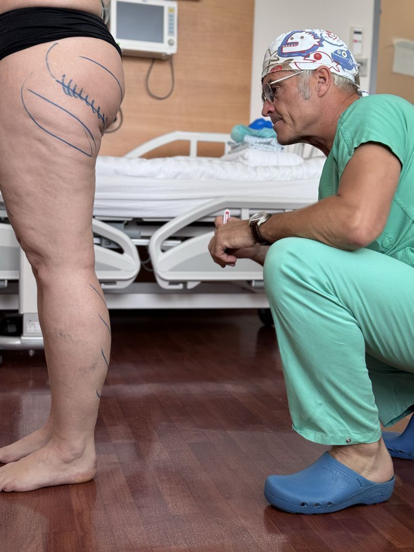 Ein Chirurg kniet nieder, um das Bein einer Frau zu untersuchen