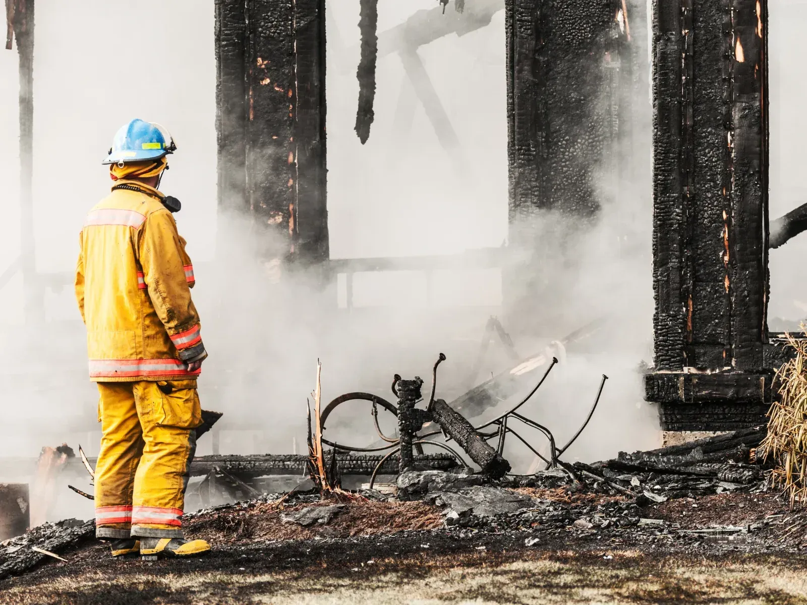 Fire fighter taking checking for heat spots post burning building.