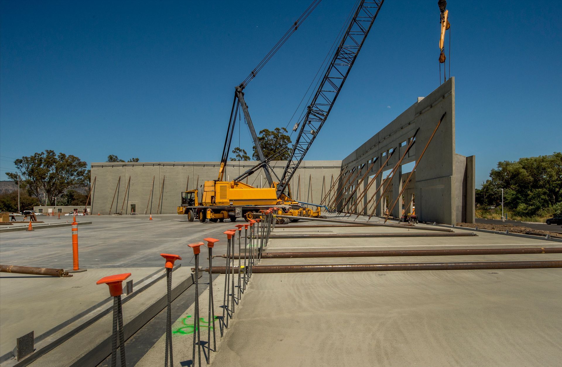 A crane is lifting a concrete wall on a construction site.