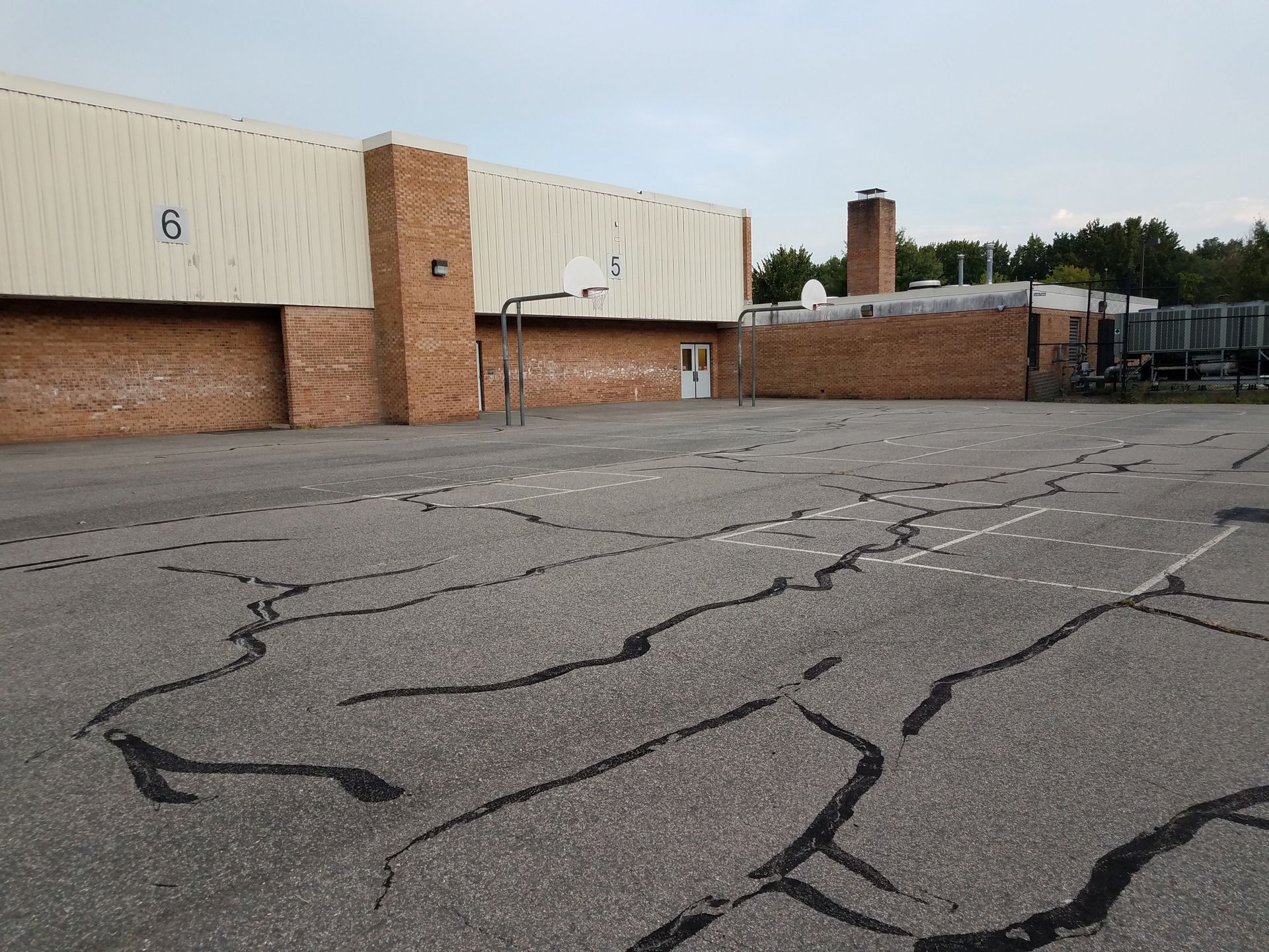 An empty basketball court in front of a brick building