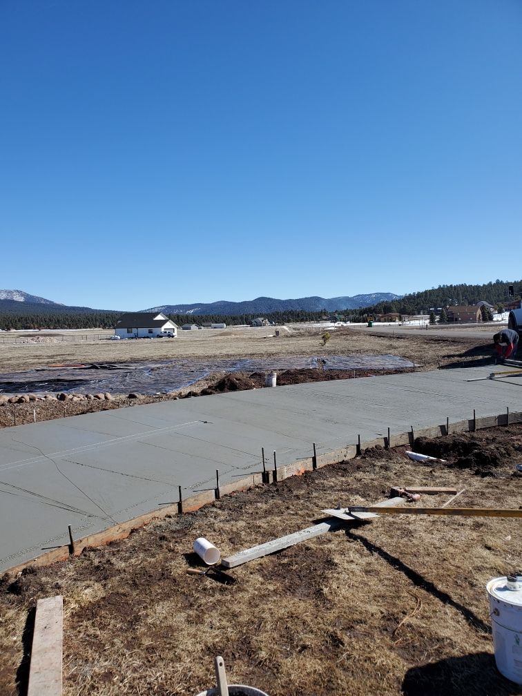 A man is spreading concrete on a sidewalk with a trowel.