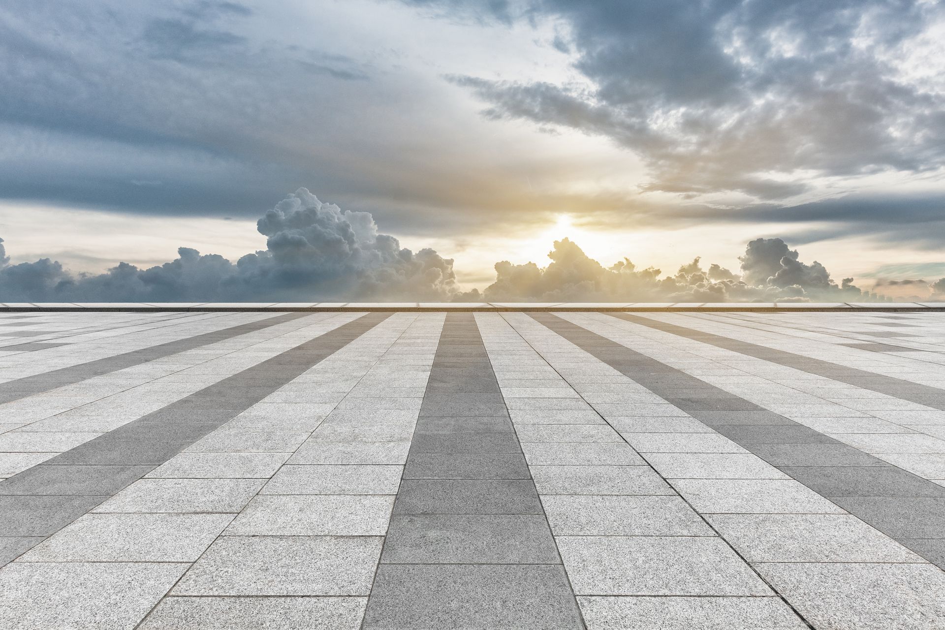 An empty tiled floor with a cloudy sky in the background.