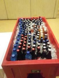 Red crate filled with assorted bottled drinks arranged in rows on a floor.