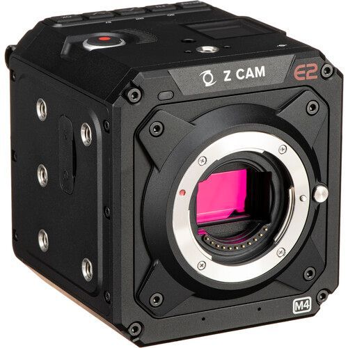 A black camera with a pink lens is sitting on a white surface.
