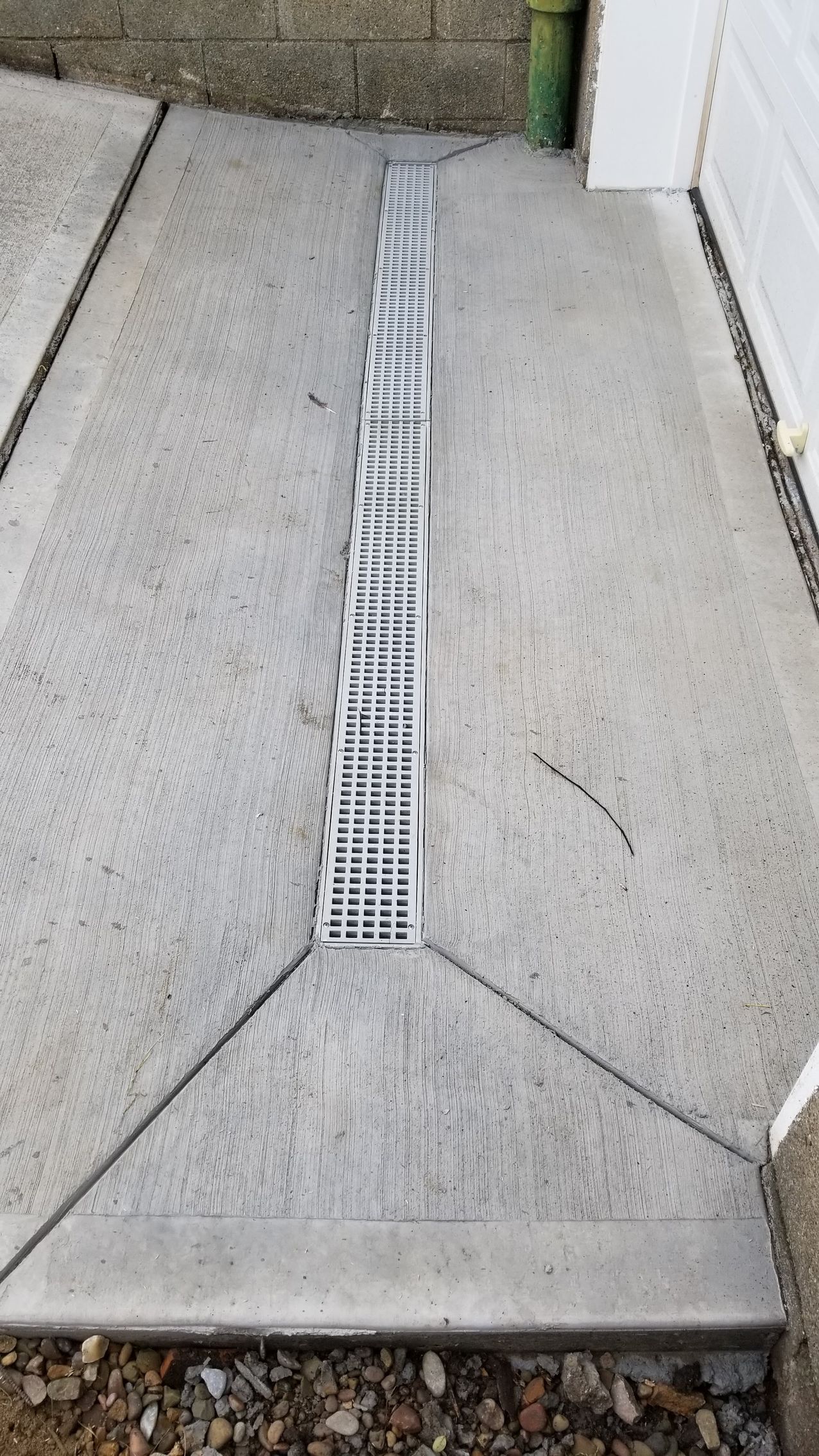 Concrete walkway with a central, grated drain.