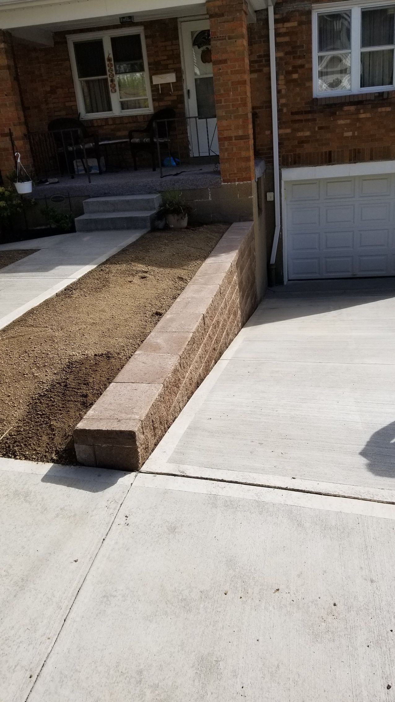 Driveway with retaining wall and gravel leading to a house entrance.