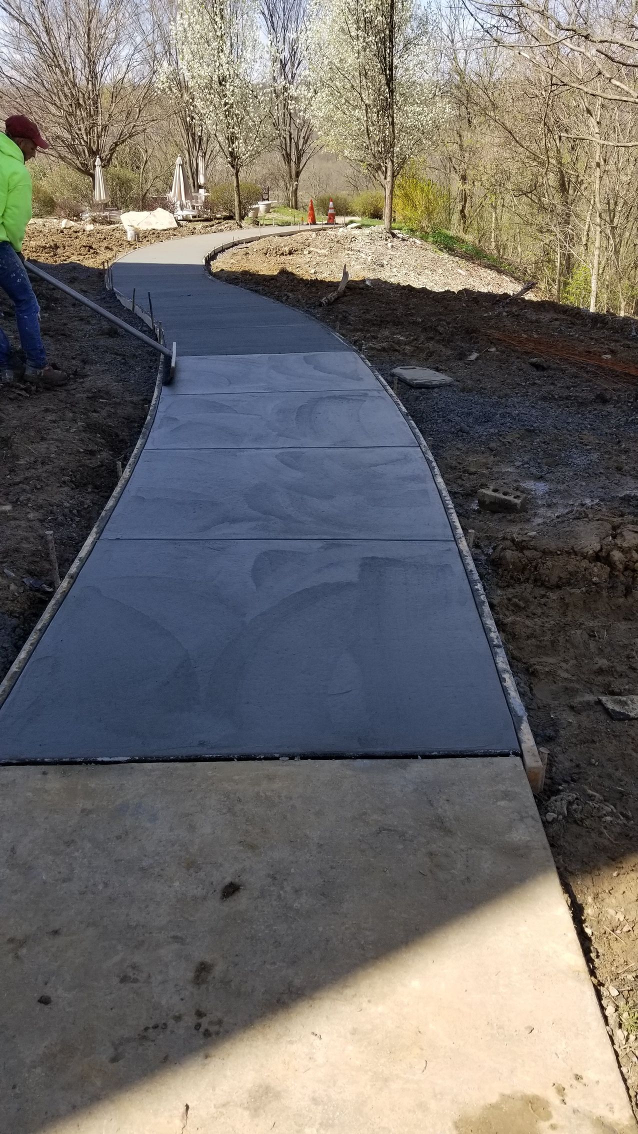 Newly poured concrete walkway with person working.