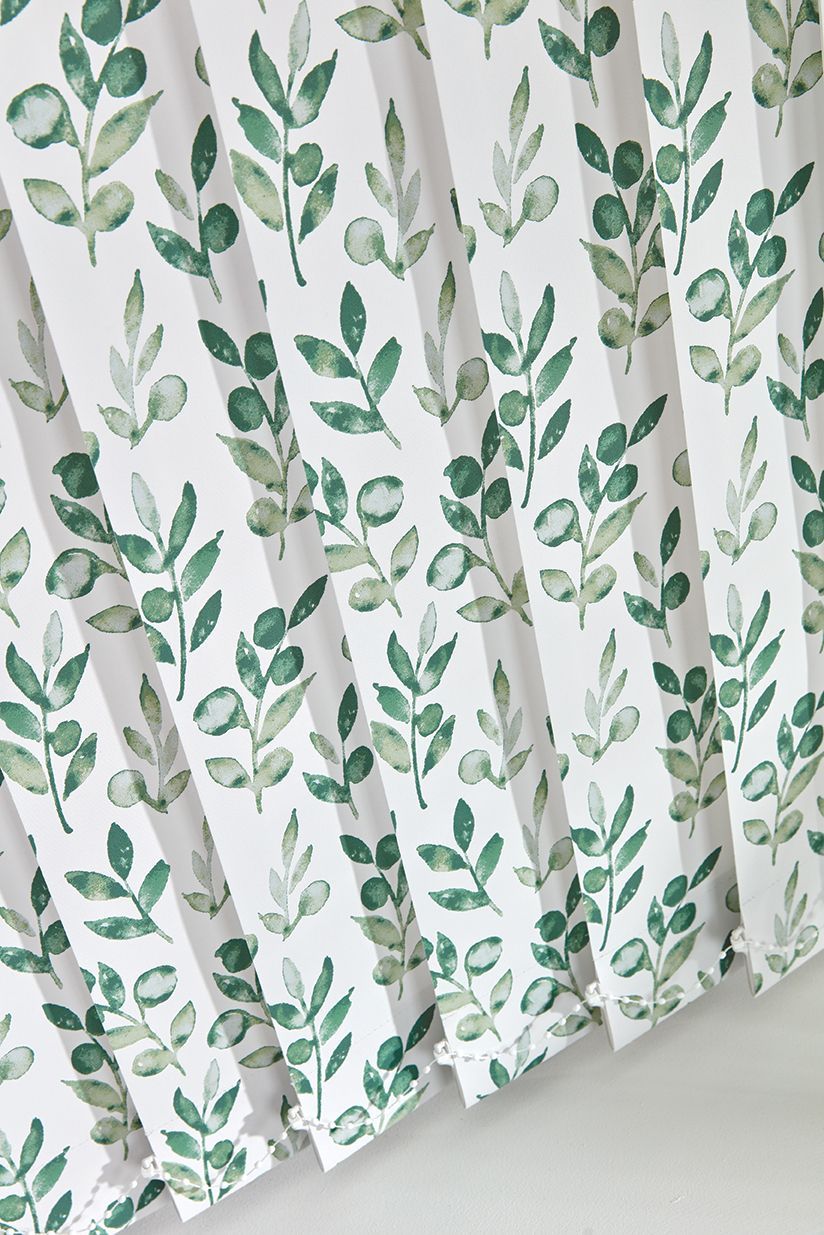 A close up of a white blind with green leaves on it.