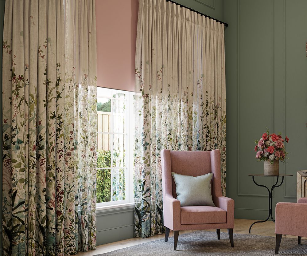 A living room with a pink chair and a window with curtains.