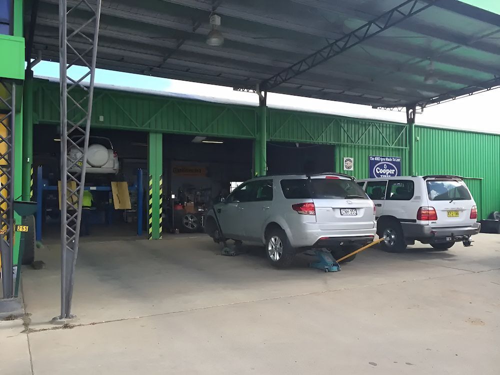A Row Of Cars Are Parked In Front Of A Green Building — Bones Tyres in Armidale, NSW
