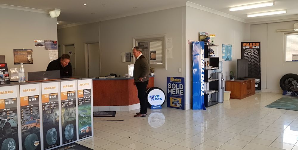 A Man Standing In Front Of A Sign That Says Sold Here — Bones Tyres in Armidale, NSW