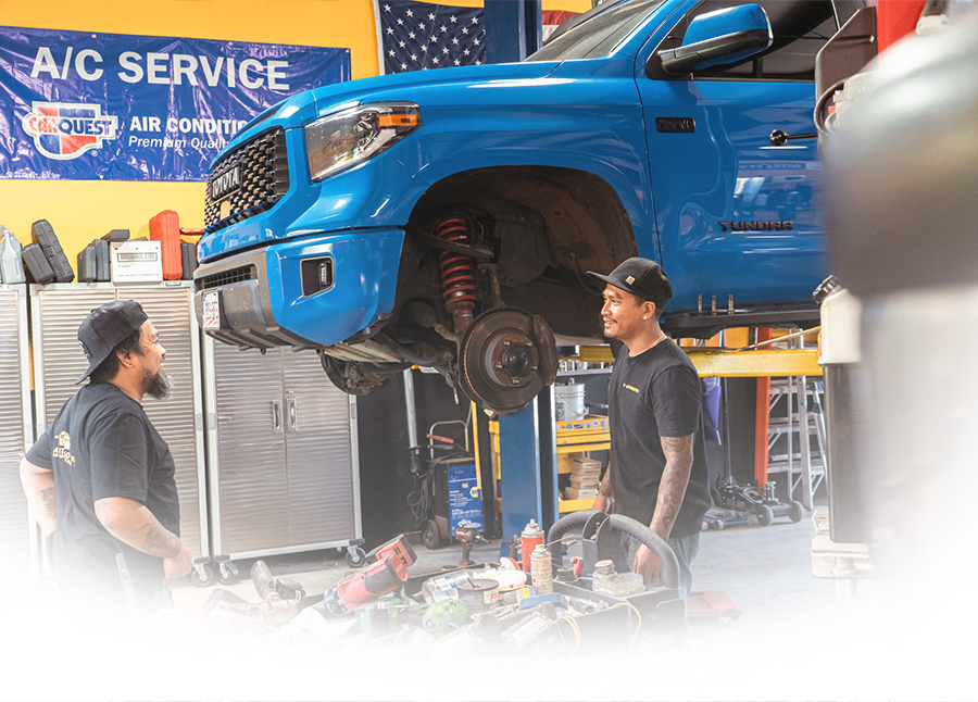 Two men are working on a car engine in a garage. | VP Automotive