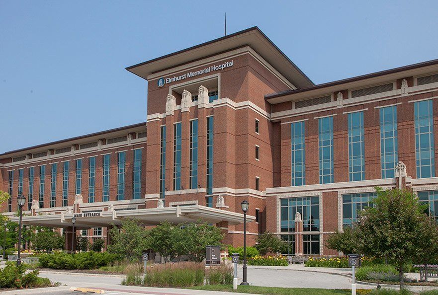 A large brick building with a lot of windows and trees in front of it.