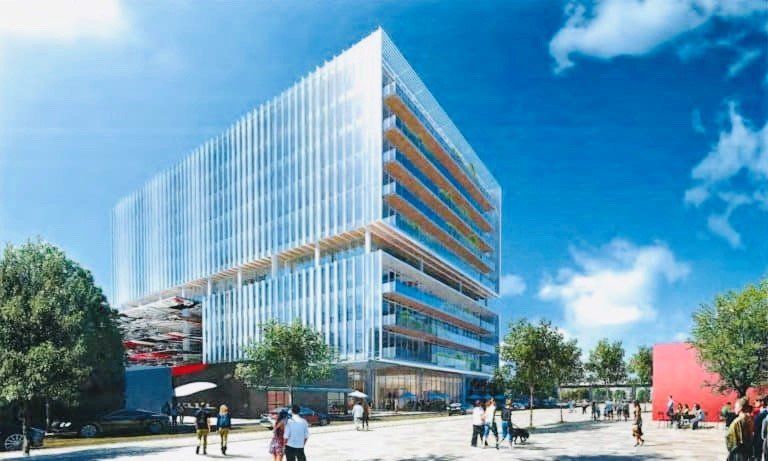 A large building with a lot of windows is surrounded by trees and people.