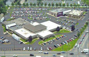 An aerial view of a large building with a lot of cars parked in front of it