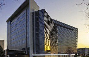 A large building with a lot of windows and a bridge in front of it.
