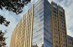 A tall building with a lot of windows is surrounded by trees.