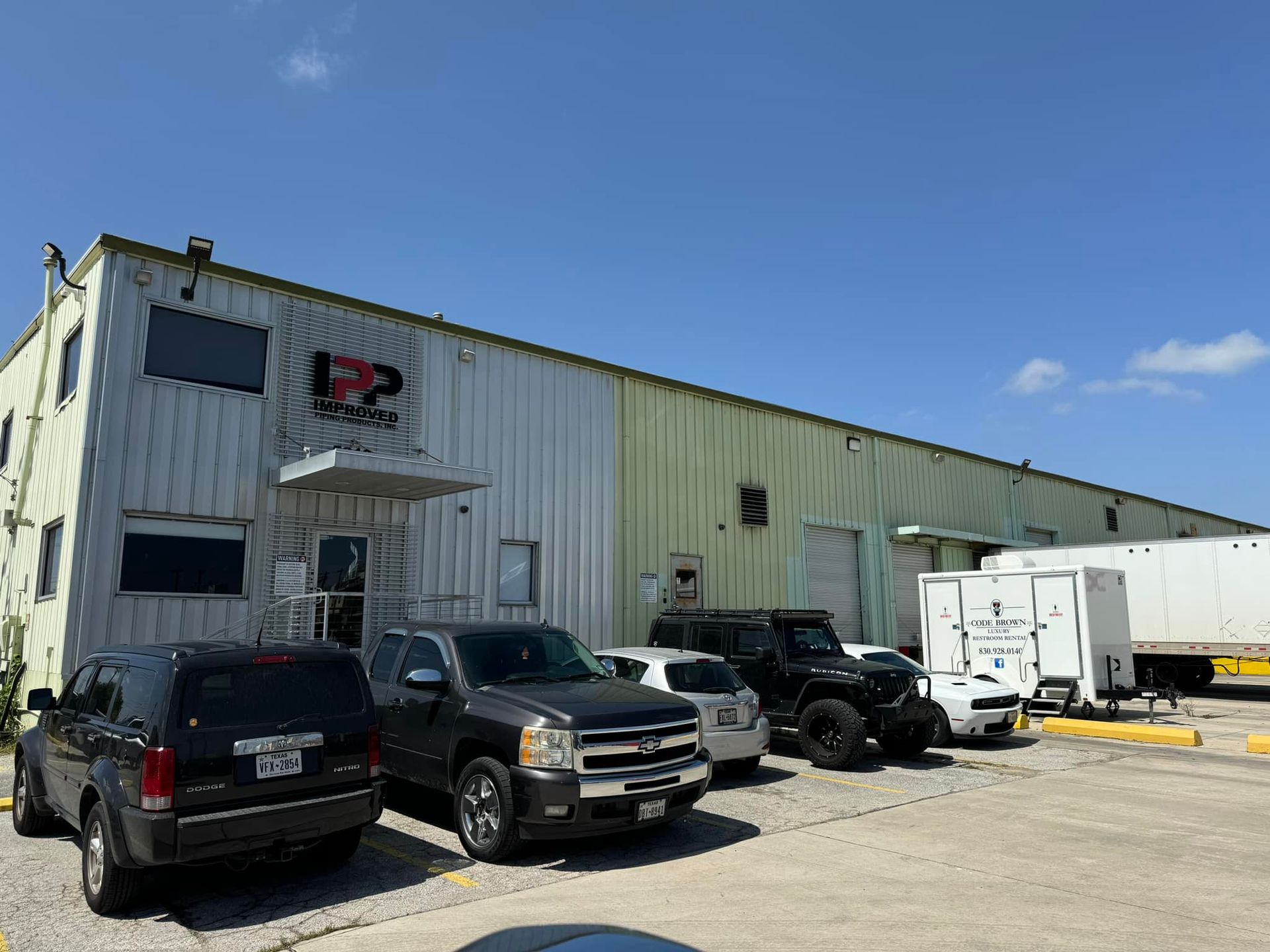 Industrial warehouse lot with parked trucks and trailers under a blue sky