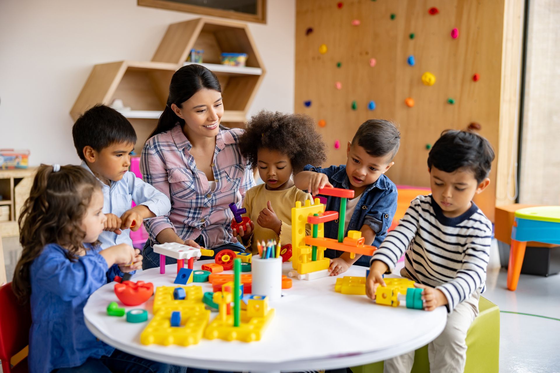 Teacher engaging with elementary students playing with toy blocks at a day care in Thomasville, NC.