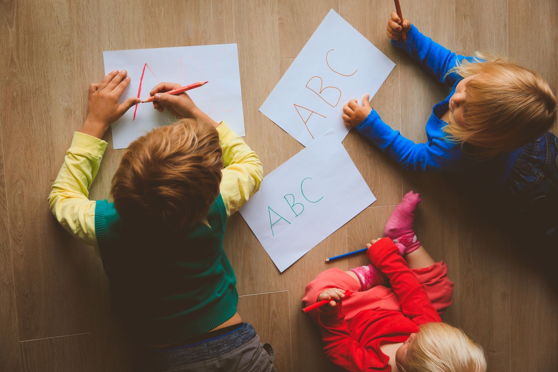 A group of children lying on the floor writing on paper, Day Care Thomasville Nc, Lexington, NC